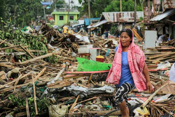 امرأة تسير قرب حطام منزلها بعدما ضرب إعصار كاموري بلدة سورسوغون في جنوب العاصمة الفلبينية مانيلا في 3 ديسمبر 2019