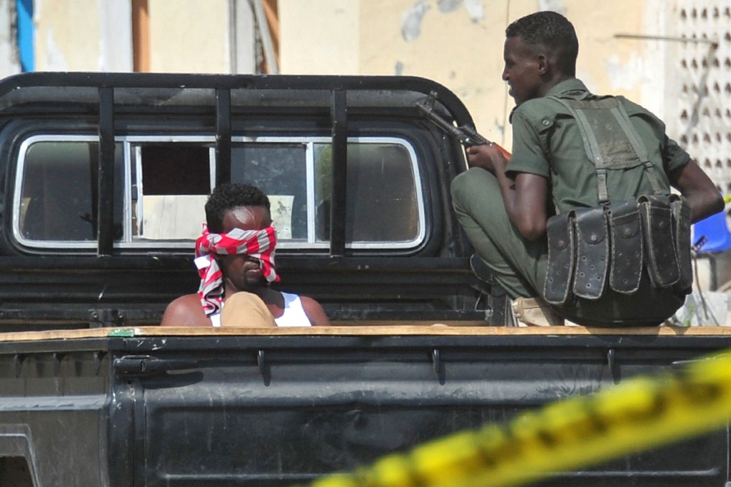 جندي صومالي يحرس معتقلا يعتقد انه تابع لحركة الشباب بعد اعتداء في مقديشو