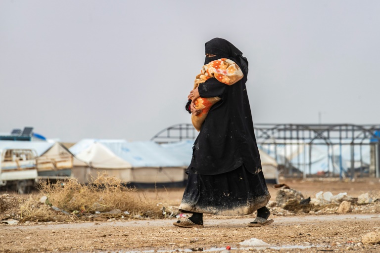 امرأة تحمل رضيعاً في مخيم الهول للاجئين الذي يديره الأكراد وحيث تحتجز عائلات مقاتلي تنظيم الدولة الإسلامية في محافظة الحسكة شمال شرق سوريا في 9 كانون الأول/ديسمبر 2019.