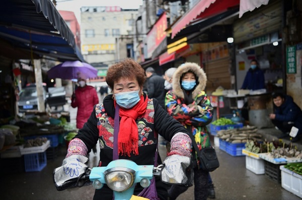 امرأة تضع قناعاً واقياً أثناء قيادة دراجتها النارية في سوق في ووهان في وسط الصين في 24 يناير 2020