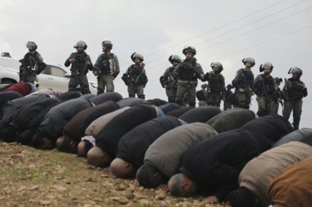 فلسطينيون يؤدون الصلاة وسط مراقبة من جنود إسرائيليين