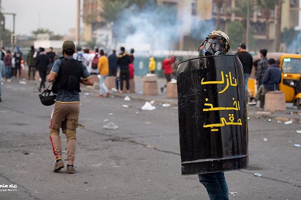 متظاهر عراقي يحمل درعا للحماية من رصاص الأمن والمليشيات المرافقة لها