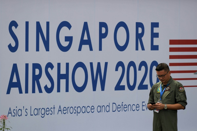 عضو من القوات الجوية السنغافورية إلى جانب ملصق للمعرض الجوي في 9 شباط/فبراير 2020