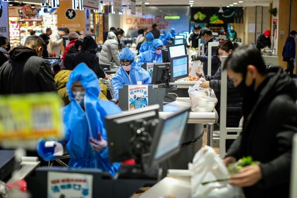 عاملون في متجر في شينيانغ في مقاطعة لياونينع في شمال شرق الصين يرتدون بزة وقائية في 10 فبراير 2020
