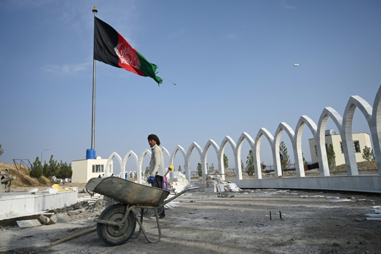 رجل يعمل في موقع ورشة إنشاءات قرب كابول وبجانبه العلم الأفغاني مرفرفا في 29 أيلول/سبتمبر 2019