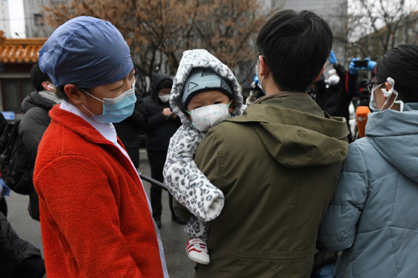 أفراد عائلة يرتدون أقنعة واقية ويغادرون مستشفى في بكين بعد شفائهم من فيروس كورونا المستجدّ في 14 فبراير 2020