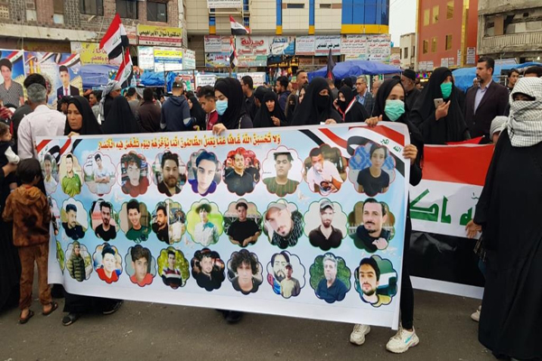 متظاهرون عراقيون يحملون صورًا لناشطين اغتالتهم الميليشيات الموالية لإيران