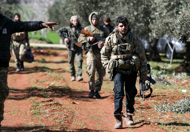 مقاتلون من فصيل معارض يسيرون في 26 شباط/فبراير 2020 بين اشجار الزيتون لدى استعدادهم للهجوم ضد قوات النظام في مدينة سراقب في شمال غرب سوريا