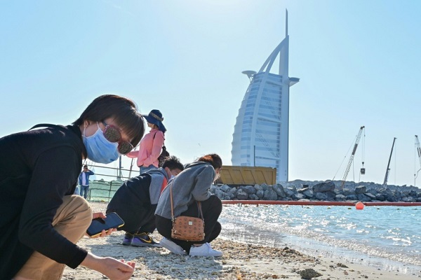 سياح يرتدون أقنعة على شاطئ بجوار برج العرب في دبي في 29 يناير 2020