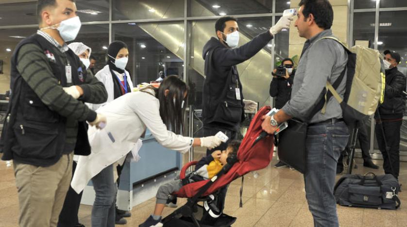 موظفو هيئة الحجر الصحي المصرية يقيسون درجة حرارة المسافرين القادمين في مطار القاهرة الدولي (أ.ف.ب)