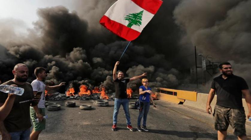 مواطن يحمل العلم اللبناني في تظاهرة منددة بفرض ضرائب جديدة في بيروت (أ.ف.ب)