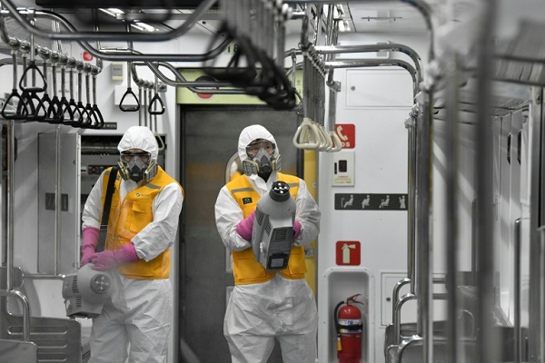 عاملان يرشان مواد معقمة داخل قطار في سيول لمنع انتشار فيروس كوفيد-19، في 11 مارس 2020