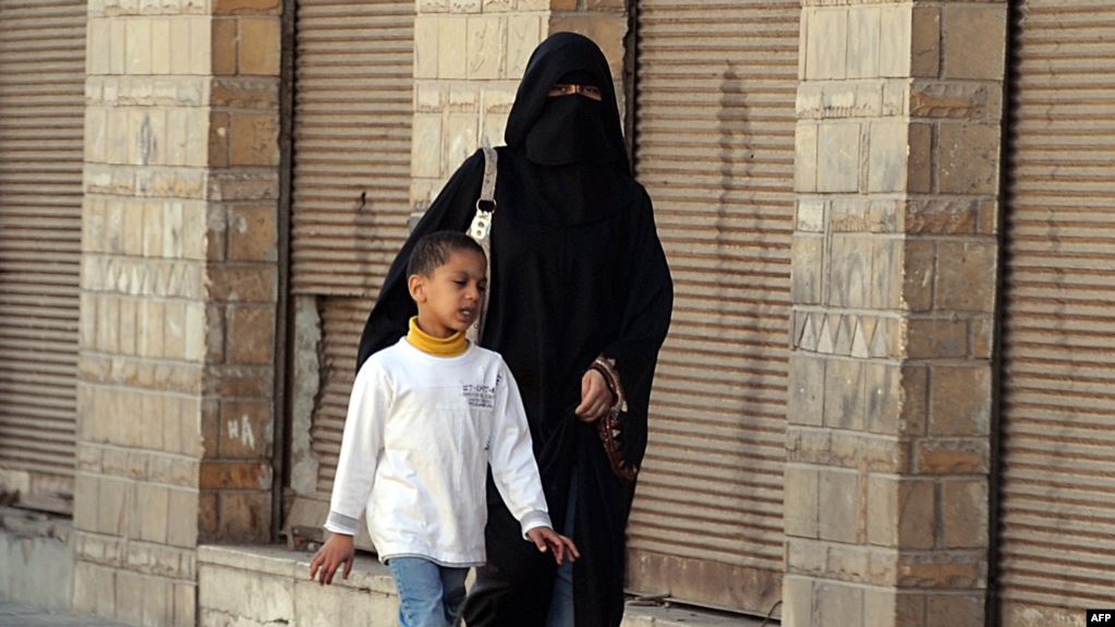 سيدة وطفلها يسيران في أحد شوارع القطيف