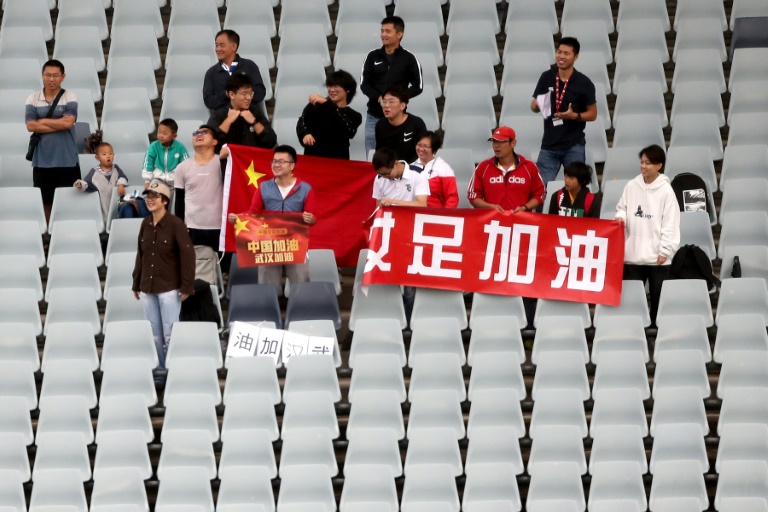 صورة تعود الى 7 فبراير 2020 في سيدني لمشجع صيني (وسط يسارا) يحمل لافتة تشجيع لمدينة ووهان