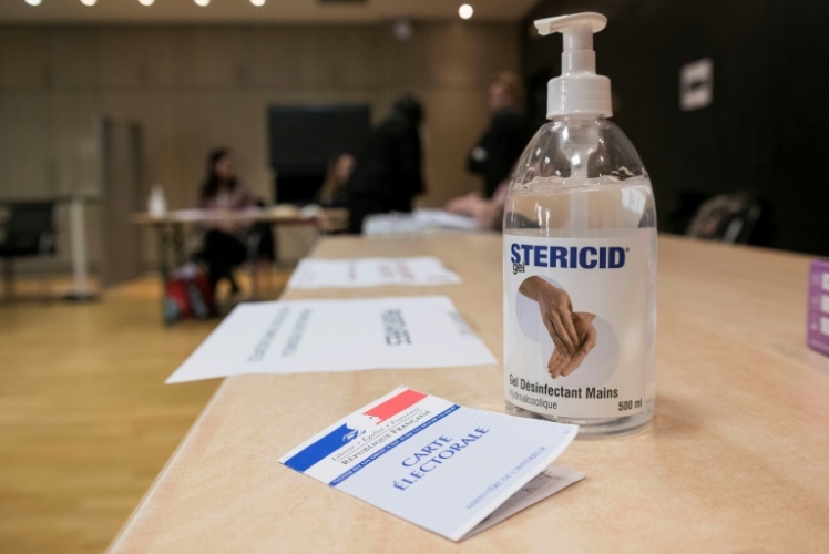 صورة تظهر معقماً لليدين قرب بطاقة انتخابية في مركز تصويت في مولهاوس في شرق فرنسا في 15 مارس 2020