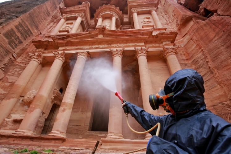 عامل يرش مادة معقمة في مدينة البتراء الأثرية جنوب العاصمة عمان