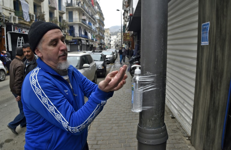 جزائري يطهر يديه بجل كحولي مربوط بعمود في حي باب الواد بالجزائر العاصمة يوم 20 آذار/مارس 2020
