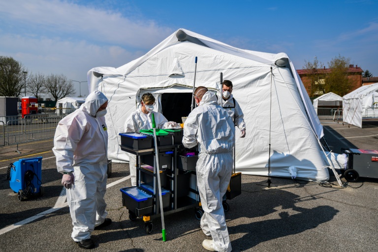 طاقم نظافة يستعد لتعقيم خيمة في مستشفى ميداني جديدة جنوب شرق ميلانو، 20 آذار/مارس 2020.