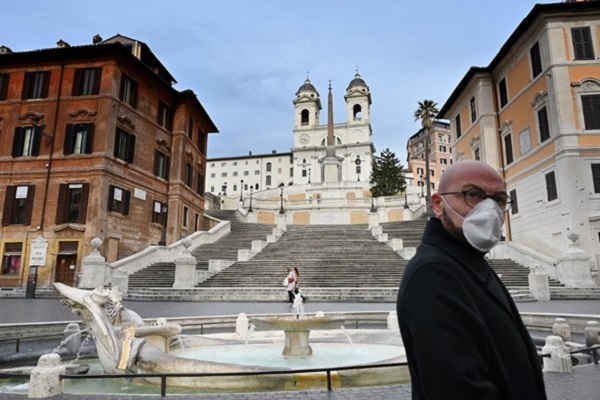 رجل يرتدي قناعاً واقياً في ساحة مهجورة بسبب كورونا وسط روما