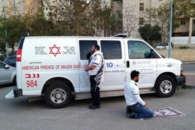 صورة نشرتها "جمعية درع داود الأحمر" في 24 آذار/مارس 2020، تظهر ممرضين يصليان أمام سيارة الإسعاف في مدينة بئر السبع (بئير شڤع)