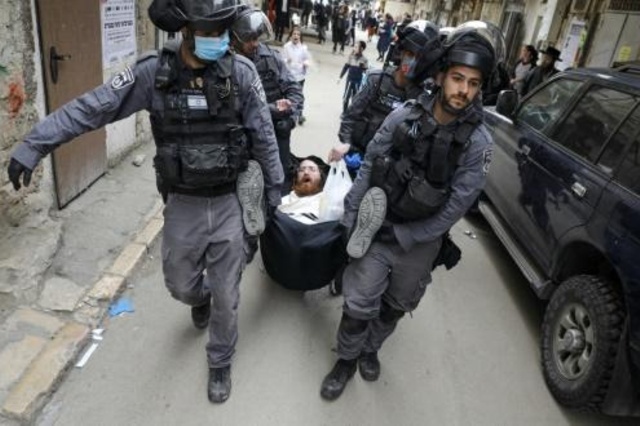 عناصر شرطة إسرائيليون يعتقلون رجلا في حي ميئاه شعارين الذي يعيش فيه يهود متدينون في القدس في 30 آذار/مارس 2020