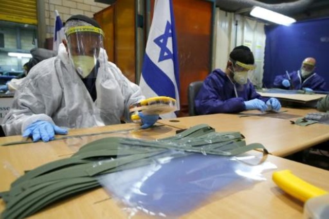 عمال مدنيون في قاعدة تل هشومير الاسرائيلية يصنعون كمامات واقنعة واقية