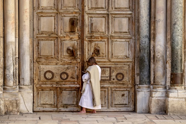 مصلٍ يقف أمام أبواب كنيسة القيامة في البلدة القديمة في القدس الشرقية المحتلة، والمغلقة بسبب تفشي فيروس كورونا المستجد في 4 أبريل 2020