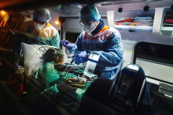 عاملان صحيان إلى جانب مريض يشتبه بأنه مصاب بفيروس كورونا في باريس