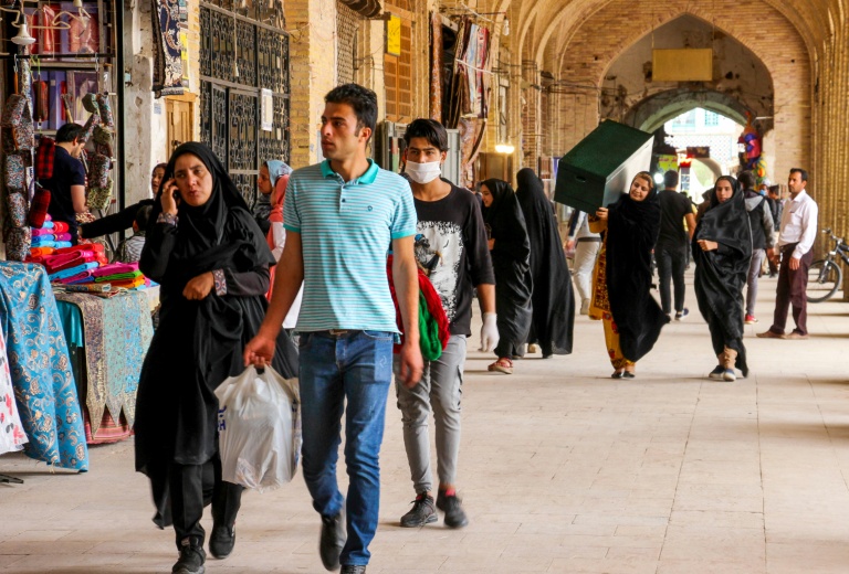 ايرانيون يمرون من امام متاجر في كرمان بتاريخ 11 نيسان/أبريل 2020