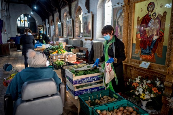 متطوعون يقدمون موادَّ غذائية في بنك طعام أقيم في كنيسة في شرق لندن في 26 مارس 2020
