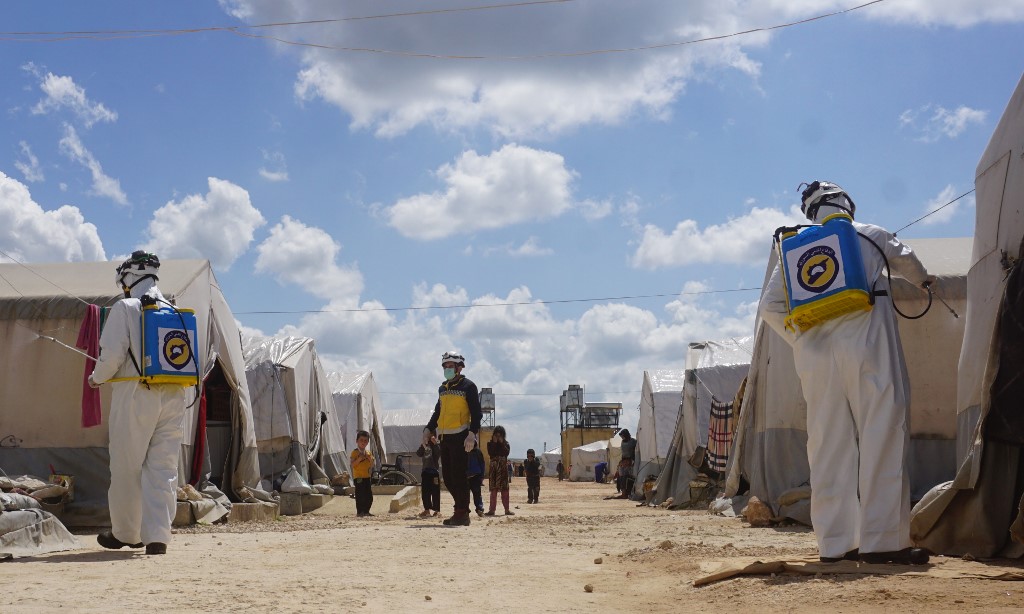 الدفاع المدني السوري يقوم بتعقيم مخيّم للاجئين قرب الحدود السورية التركية