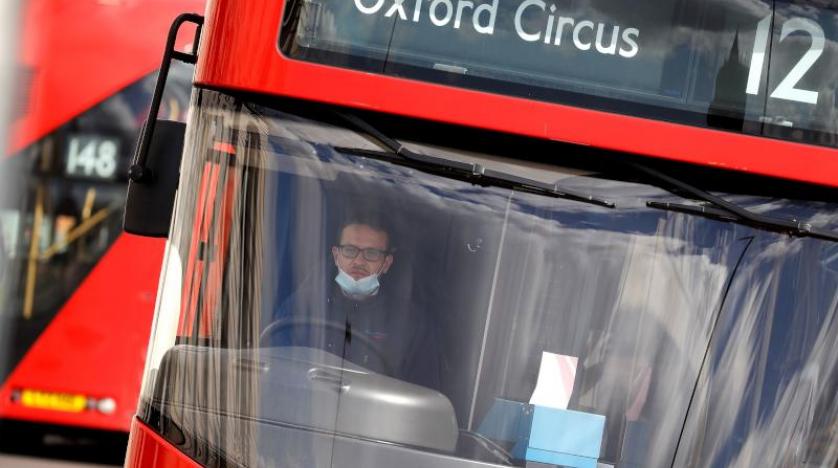 سائق حافلة في لندن يضع قناع وجه كإجراء وقائي ضد فيروس «كورونا» (أ.ف.ب)