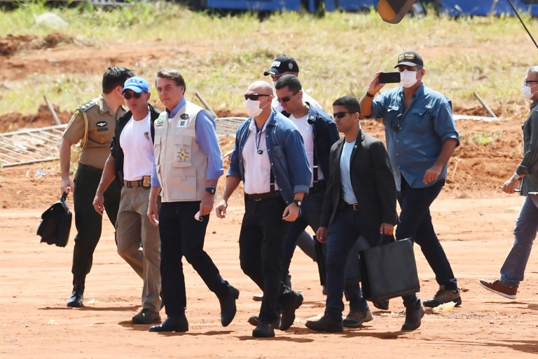 الرئيس البرازيلي (الثالث من اليسار) الذي استهزأ بإجراءات التباعد الاجتماعي يظهر بدون كمامة أثناء زيارته موقع مستشفى ميداني