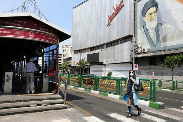 إيرانية تعبر شارعاً في طهران وخلفها صورة للمرشد الأعلى الإيراني آية الله علي خامنئي في 21 أبريل 2020