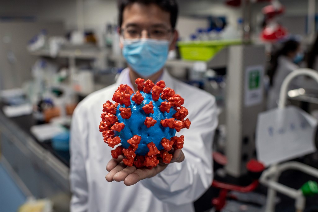 باحث في مختبر صيني يعرض مجسما بلاستيكيا لفيروس كورونا المستجدّ