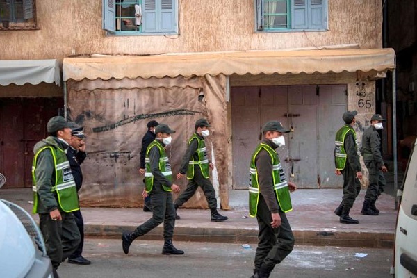 أفراد من الشرطة المغربية يحضّون المواطنين في أحد أحياء الرباط على البقاء في المنازل