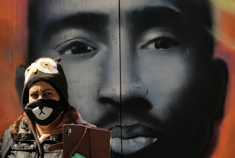 امرأة تضع كمامة تلتقط صورة لنفسها أمام جدارية لمغني الراب الراحل توباك شاكور في حي هارلم النويوركي في 5 أيار/مايو.