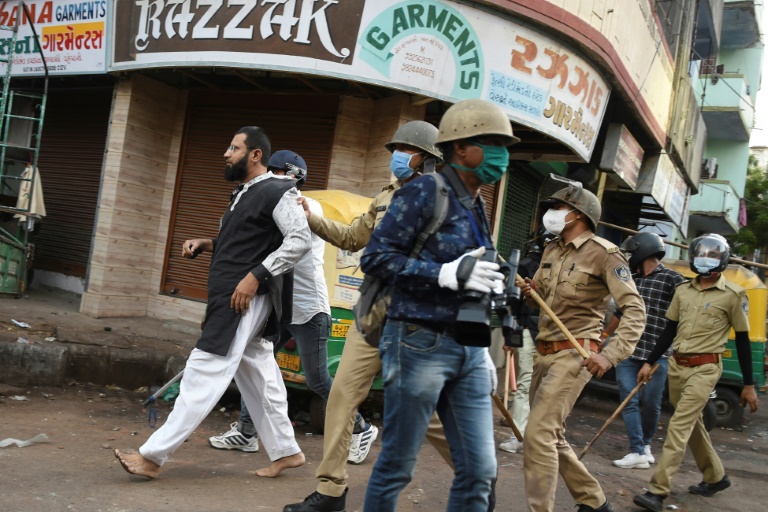 الشرطة في غوجارات تقتاد شخصا كان يرشقها بالحجارة في منطقة شهبور، خلال تدابير الإغلاق المفروضة للحد من تفشي فيروس كورونا، في 8 أيار/مايو 2020
