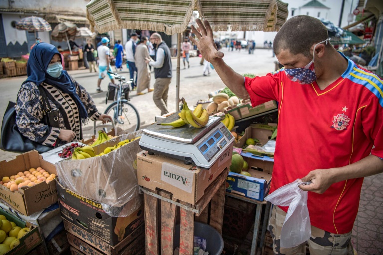 بائع يرتدي قناعًا واقيًا، يزن الموز في السوق المركزي خلال شهر رمضان المبارك في العاصمة المغربية الرباط في 6 أيار/مايو 2020