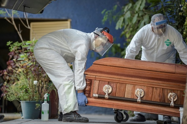 موظفون في دار لدفن الموتى ينقلون تابوتاً لحرق الجثمان الموجود بداخله في المكسيك