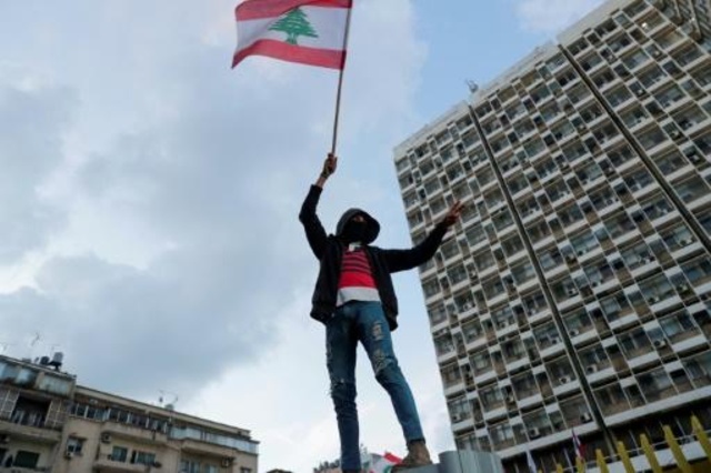 متظاهر يرفع العلم اللبناني خلال تظاهرة قبالة مؤسسة كهرباء لبنان في بيروت، 11 كانون الثاني/يناير 2020