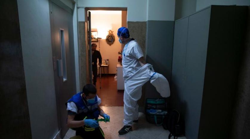 عمال من الرعاية الصحية في منزل مريض بكورونا في برشلونة (أ.ف.ب)