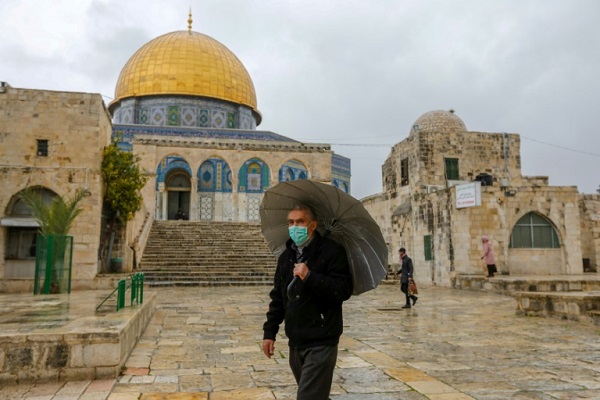 فلسطيني يضع كمامة وقائية من كورونا يسير أمام مسجد قبة الصخرة في القدس الشرقية