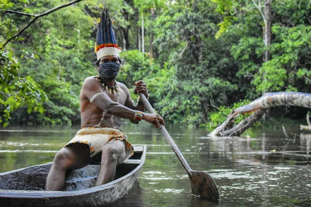 أحد سكان كولومبيا الأصليين يرتدي قناعا واقيا ويعبر نهرا 