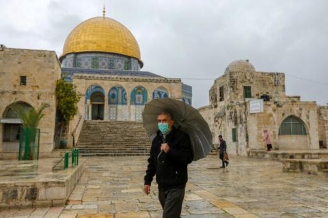 فلسطيني يضع كمامة وقائية من فيروس كورونا المستجد يسير أمام مسجد قبة الصخرة في القدس الشرقية المحتلة في 20 آذار /مارس 2020
