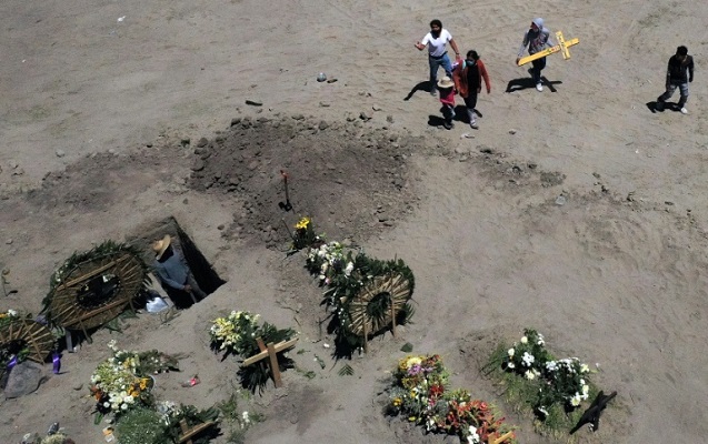 أقرباء أحد ضحايا كوفيد-19 يحملون الصليب في مقبرة في فالي دي شالكو بالمكسبك