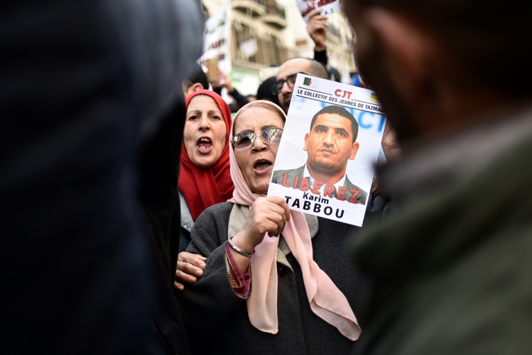 متظاهرة جزائرية ترفع صورة الناشط كريم طابو مطالبة بالافراج عنه