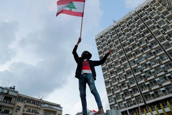 متظاهر يرفع العلم اللبناني خلال تظاهرة قبالة مؤسسة كهرباء لبنان في بيروت