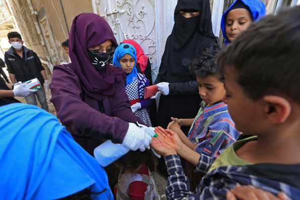 أم يمنية تعقّم أيادي أطفالها (أ ف ب)