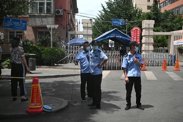 رجال شرطة يضعون الكمامات ويقفون أمام منطقة تخضع لإغلاق في بكين